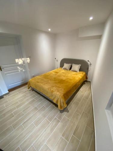 - une chambre avec un lit et une couverture jaune dans l'établissement Au coeur de Brantôme : superbe appartement, à Brantôme