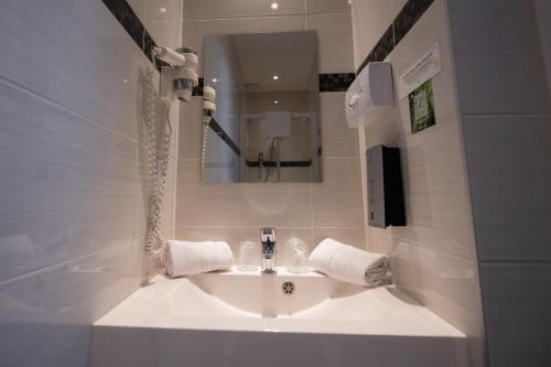 een badkamer met een witte wastafel en een spiegel bij Logis Hotel Le Continental in Châteauroux