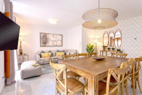 comedor y sala de estar con mesa de madera y sillas en Genteel Home Tetuan Marbella, en Marbella