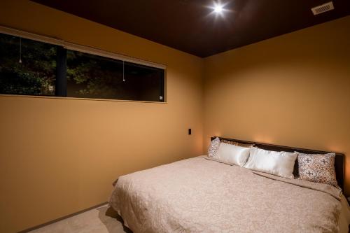 a bedroom with a bed and a window at 1日1組限定 展望露天風呂付き 南国リゾート貸切ヴィラ 歩羅无 湯河原 FuranYugawara in Yugawara