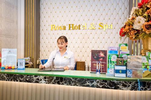 a woman sitting at a table with a laptop at Rosa Hotel & Spa in Ho Chi Minh City