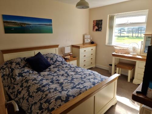 a bedroom with a bed and a desk and a window at Harlech apartment Castle view in Harlech