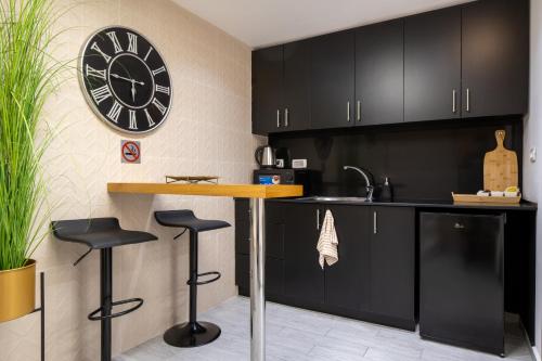 a kitchen with black cabinets and a clock on the wall at Amazing Atmosphere- Bahai Gardens Main Street in Haifa
