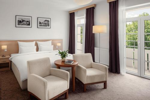 a hotel room with a bed and two chairs and a table at Harvey Spa Hotel in Františkovy Lázně