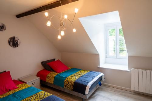 - une chambre mansardée avec 2 lits et un lustre dans l'établissement Le champ bourdon, à Saint-Maur-des-Bois