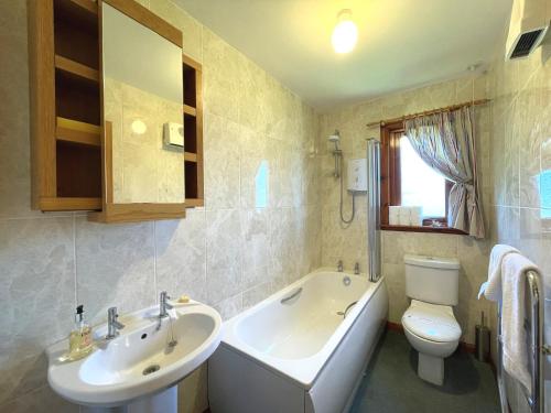 a bathroom with a tub and a sink and a toilet at Pass the Keys Beautiful Golf and Beach Lodge in Stunning Location in Dalbeattie