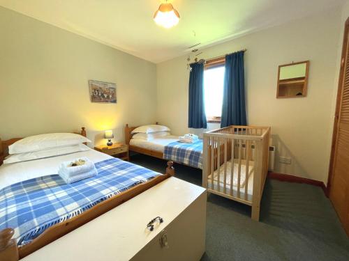 a bedroom with two beds and a crib in it at Pass the Keys Beautiful Golf and Beach Lodge in Stunning Location in Dalbeattie