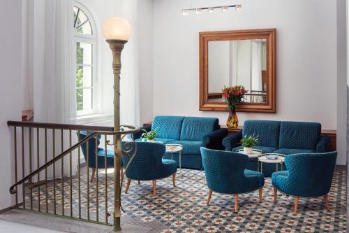 a living room with blue chairs and a mirror at Harvey Spa Hotel in Františkovy Lázně