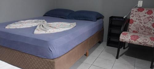 a bed in a room with a chair and a bedskirtspectspectspectspects at POUSADA DONA ELVIRA in Capão da Canoa