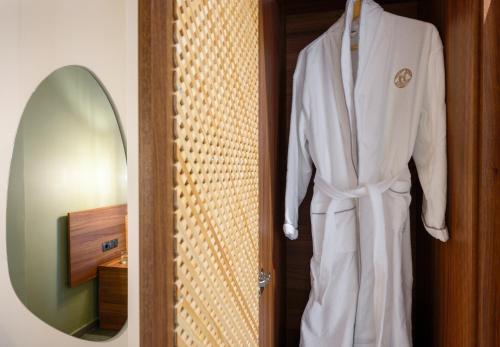a white robe hanging on a door next to a mirror at Amyntas Seafront Hotel in Neos Marmaras