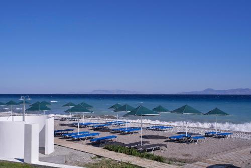 uma praia com cadeiras e guarda-sóis e o oceano em Labranda Blue Bay Resort em Ialyssos