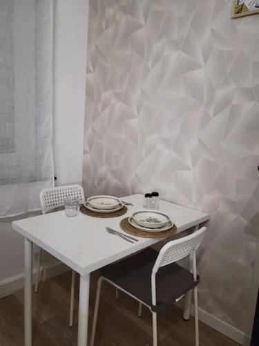 una mesa blanca con 2 platos y 2 sillas en Bel appartement moderne, en Marly