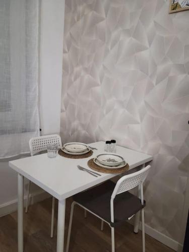 une table blanche avec deux assiettes et deux chaises dans l'établissement Bel appartement moderne, à Marly