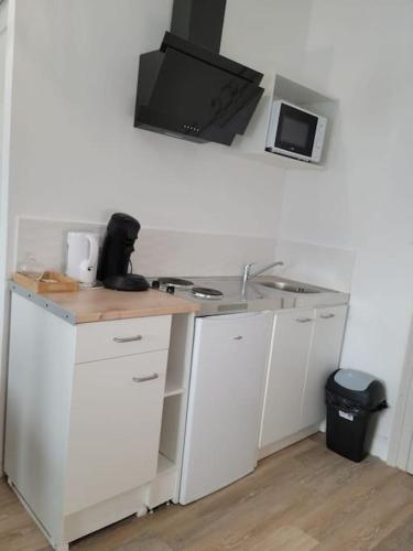 cocina blanca con fregadero y microondas en Bel appartement moderne, en Marly
