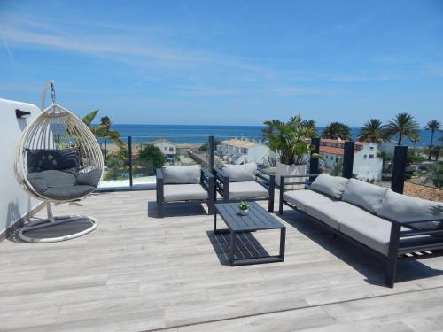 a patio with a couch and a swing and the ocean at Exclusivo Ático de Lujo en la Playa - holaVivienda Inmobiliaria in Denia