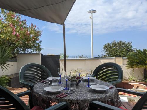 a table with wine glasses and an umbrella on a patio at Havre de Paix sur la Côte Bleue in Sausset-les-Pins