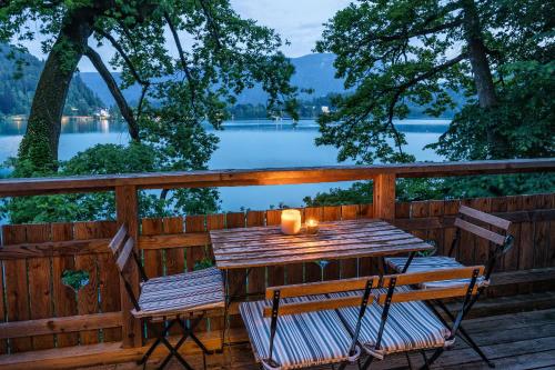 a wooden table and chairs on a deck with a view of a lake at Private beach house on Lake Bled in Bled