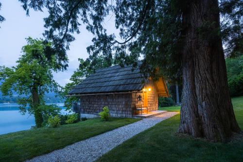 a log cabin by the water with a tree at Private beach house on Lake Bled in Bled