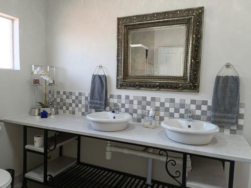 a bathroom with two sinks and a mirror at Sedgefield Lodge in Witbank