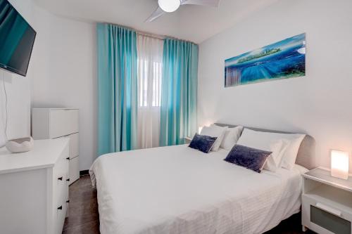 sypialnia z białym łóżkiem i niebieskimi zasłonami w obiekcie Drilasol Seaview 1A022 w mieście Puerto de Santiago