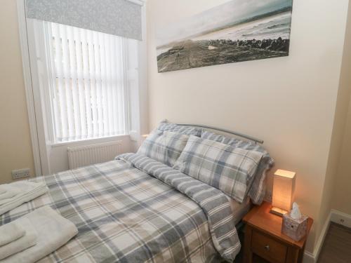 1 dormitorio con 1 cama con manta a cuadros en Amble Watch, en Morpeth