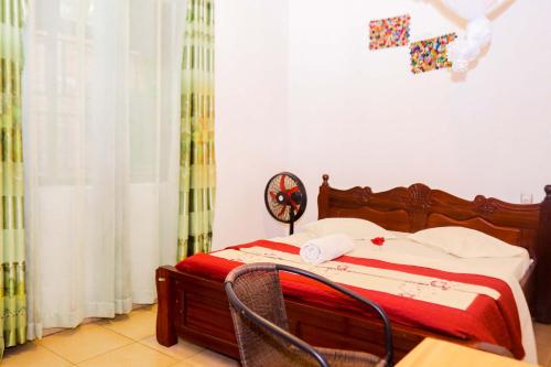 um quarto com uma cama com um cobertor vermelho em THE PILLAR MOTEL em Kigali