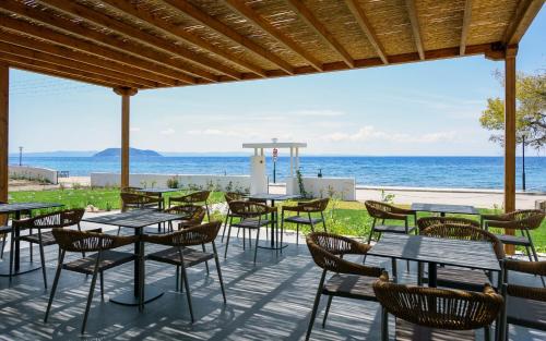 a patio with tables and chairs overlooking the ocean at Amyntas Seafront Hotel in Neos Marmaras