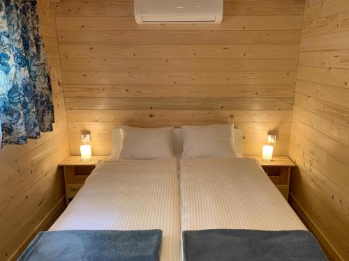 a bed in a wooden room with two lights at Modrzewiowe Zacisze in Chocieszow