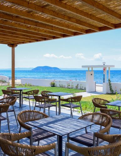 a patio with tables and chairs and the beach at Amyntas Seafront Hotel in Neos Marmaras