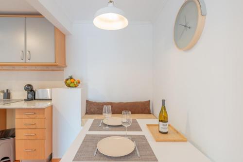 a kitchen with a table with wine glasses and a clock at Prainha Apartments in São Roque do Pico