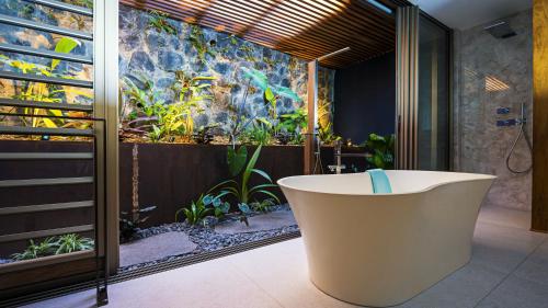 uma banheira na casa de banho com um jardim em Blue Margouillat Seaview Hotel-RELAIS & CHATEAUX em Saint-Leu