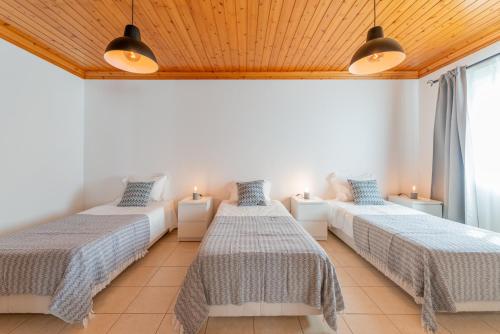 Cette chambre comprend 2 lits, 2 lampes et une fenêtre. dans l'établissement Prainha Apartments, à São Roque do Pico