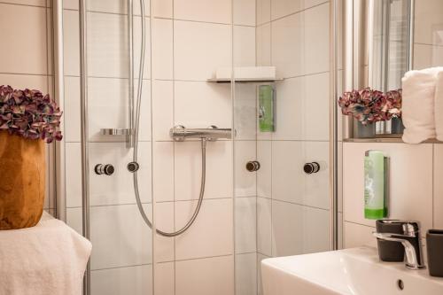 La salle de bains est pourvue d'une douche et d'un lavabo. dans l'établissement Boutique-Appartement Südblick, à Oberstdorf