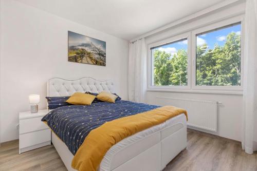 a white bedroom with a bed and two windows at Air-conditioned 75m2 apartment next to the airport - FREE PARKING in Prievoz