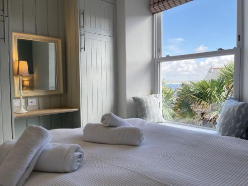 een slaapkamer met een groot raam en handdoeken op een bed bij Porth House, with south facing courtyard garden! in St Ives