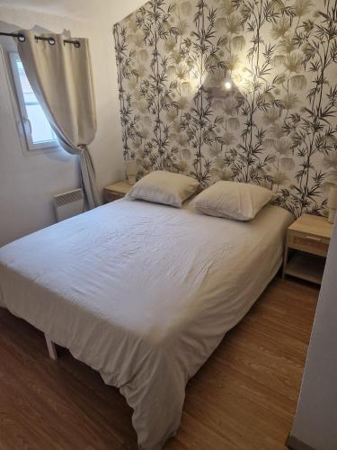 - une chambre avec un lit blanc et un papier peint floral dans l'établissement Bienvenue chez Stéphane et Marina, à Gallargues-le-Montueux