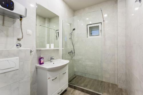 a white bathroom with a sink and a shower at Apartments Gloria in Budva