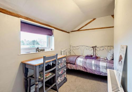a bedroom with a bed and a desk and a window at Tiggywinkles in Debenham