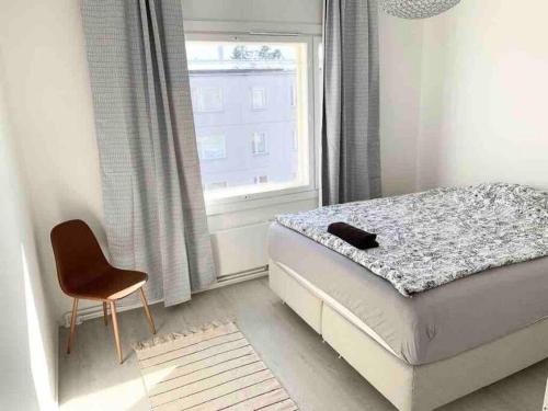 a bedroom with a bed and a chair and a window at MELLUNMAKI Renovated 3 bedroom apt next to metro in Helsinki