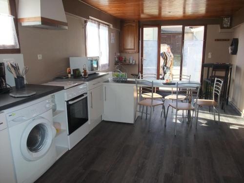 eine Küche mit einer Waschmaschine und einem Tisch mit Stühlen in der Unterkunft Gîte Mirabella 
