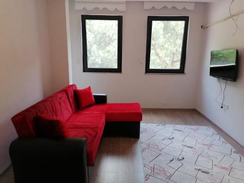 a living room with a red couch and two windows at Erme Apart Evler in Dernekpazarı