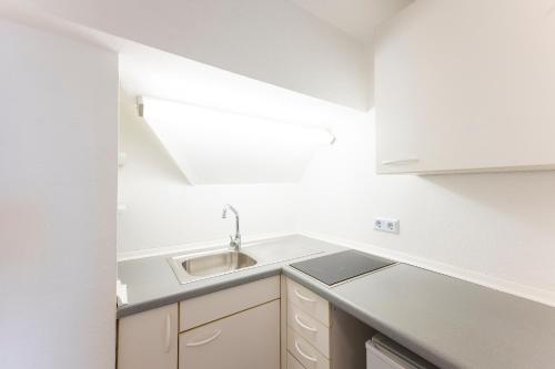 una cucina bianca con un lavello e un bancone di Hotel Astoria am Urachplatz a Stoccarda