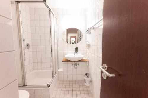 a white bathroom with a sink and a shower at Hotel Astoria am Urachplatz in Stuttgart