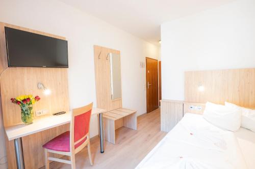 a hotel room with a bed and a desk with a television at Hotel Astoria am Urachplatz in Stuttgart