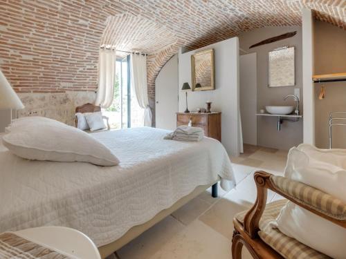 une chambre avec un grand lit et un mur de briques dans l'établissement Villa in Village with Heated Pool, à Prayssac