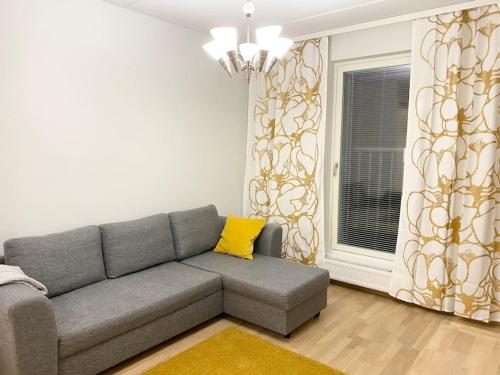 a living room with a gray couch and a yellow pillow at PEURANIITTY-2 Modern well equipped apartment in Espoo
