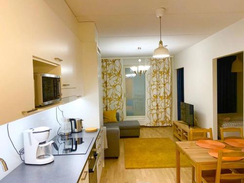 a kitchen and a living room with a table at PEURANIITTY-2 Modern well equipped apartment in Espoo