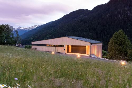 a house in a field with mountains in the background at Haus Albuin in Sankt Gallenkirch