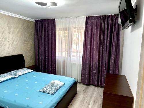 een slaapkamer met een blauw bed en paarse gordijnen bij ROYAL APARTMENT in Buzău