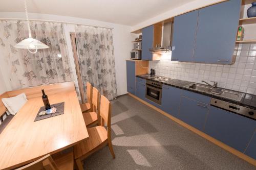 a kitchen with a wooden table and blue cabinets at Appartement Montanea in Schruns-Tschagguns